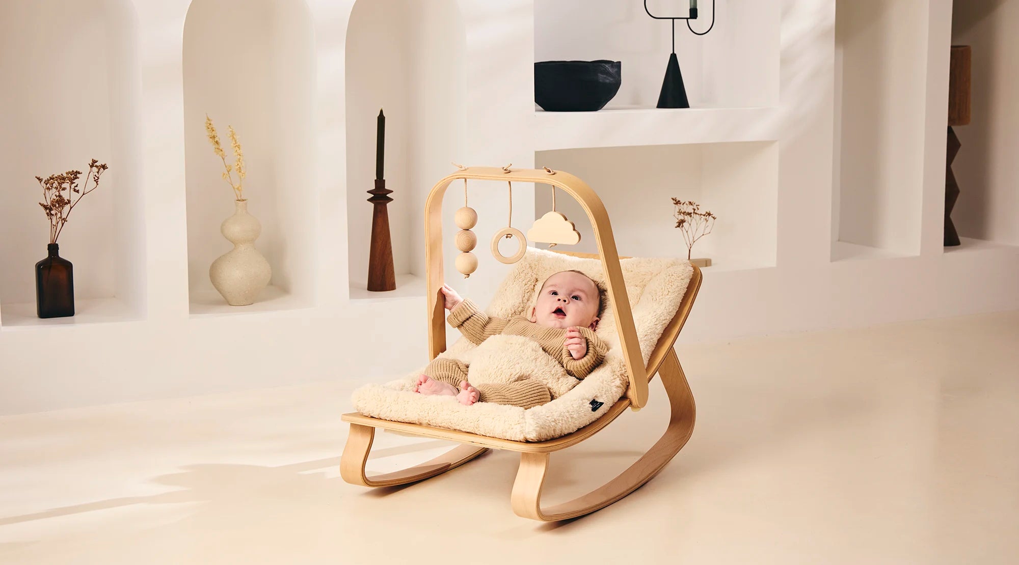 Charlie Crane LEVO rocker with fur cushion and play arch in a living room